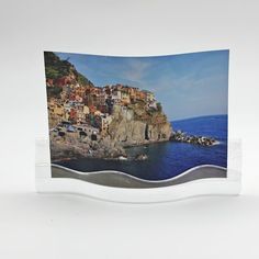 an image of a small town on the edge of a cliff by the ocean with blue water