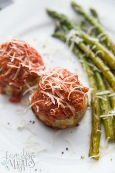 asparagus with sauce and parmesan cheese on a white plate