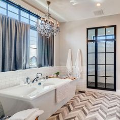 a large bathroom with a chandelier and two sinks in front of the bathtub