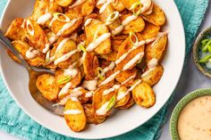 a white bowl filled with fried potatoes covered in ranch dressing