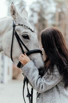 a woman standing next to a white horse