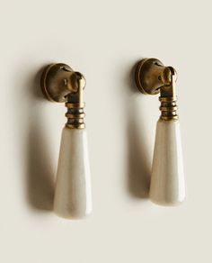 two brass and white wall lights on the side of a wall with one light turned off