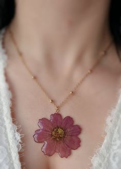 Add a touch of nature's beauty to your jewelry collection with this Pressed Cosmos Flower Necklace. This stunning necklace features a real cosmos flower that has been carefully pressed and encased in resin to preserve its natural beauty. The resin pendant is set on a golden beaded chain, creating a unique and eye-catching look. This necklace is available in two chain options - a 925 sterling silver chain or an 18k gold plated chain - so you can choose the one that best suits your style. Both cha Preserved Flower Necklace, Delicate Necklace With Pressed Flowers, Dainty Flower-shaped Necklace With Pressed Flowers, Nature-inspired Flower Pendant Necklace With Pressed Flowers, Bohemian Birth Flower Necklaces, Bohemian Birth Flower Pendant Necklace, Bohemian Necklace With Pressed Flowers, Nature-inspired Flower Necklaces With Pressed Flowers, Pink Bohemian Jewelry With Pressed Flowers