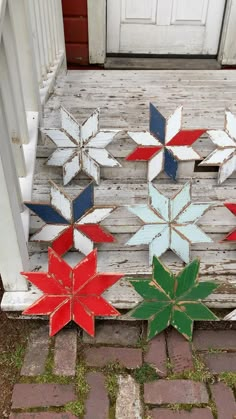 four wooden snowflakes sitting on top of a porch next to a white door