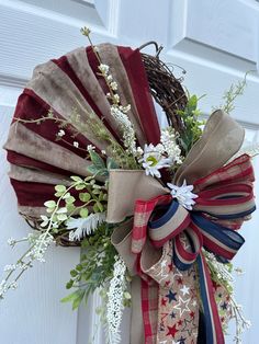 a wreath with red, white and blue ribbons hanging on the front door for memorial day