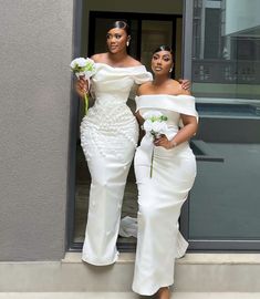 two women in white dresses standing next to each other