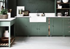 a kitchen with green painted cabinets and white counter tops is pictured in this image, there are many dishes on the shelves