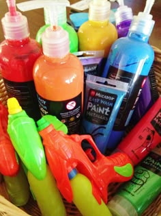 a basket filled with lots of different types of paint and glue on top of a table