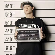 a young man holding a sign in front of a mugshot wall with the words runyon avenue written on it