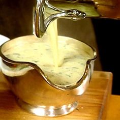 a person pouring sauce into a metal bowl