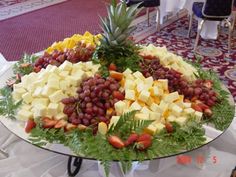 a platter filled with fruit and cheese on top of a table