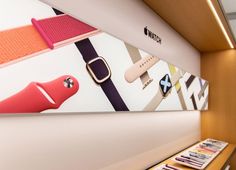 an apple watch store display with colorful bands on it's display wall and remote controls in the foreground