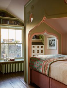 a bed sitting under a window in a bedroom next to a radiator and bookshelf