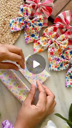 someone is making bows out of fabric and paper on a table next to some flowers