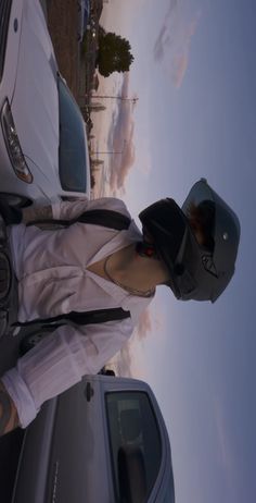 a person standing next to a car with a hat on their head and wearing a white shirt