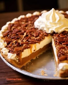 a pie with pecans and whipped cream on top is sitting on a metal platter