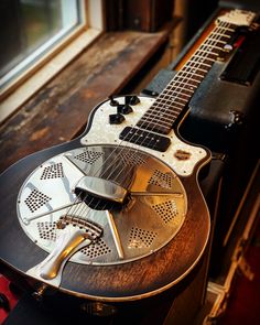 an electric guitar sitting on top of a wooden table next to a window sill