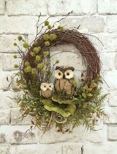 an owl wreath with two owls sitting on it's head and surrounded by greenery