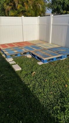 a backyard area with concrete blocks laid out in the grass and a white fence behind it