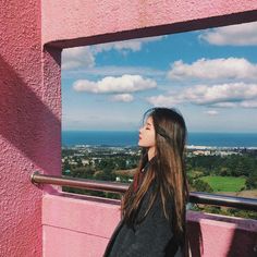 a woman standing on top of a pink building