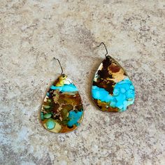 two pieces of jewelry sitting on top of a stone floor with blue and brown paint