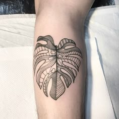 a black and white tattoo on the arm of a person with a heart shaped leaf