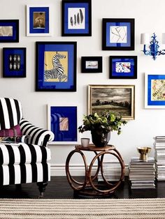 a living room with black and white striped furniture, blue framed pictures on the wall