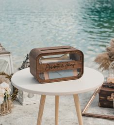 a small wooden box on top of a table next to a body of water in the background