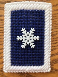 a crocheted square with a snowflake on the front and blue border