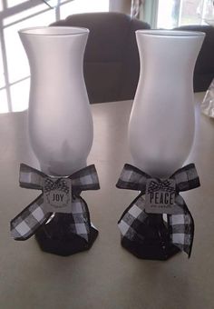 two white vases sitting on top of a table with black and white ribbon around them