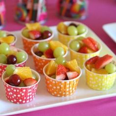 small cups filled with fruit sitting on top of a white tray next to other cupcakes