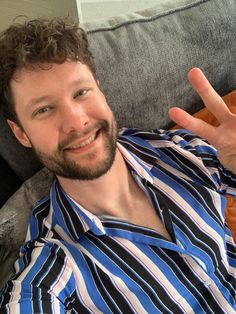 a man sitting on a couch making the peace sign