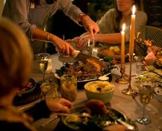 a group of people sitting around a table with food and candles in front of them