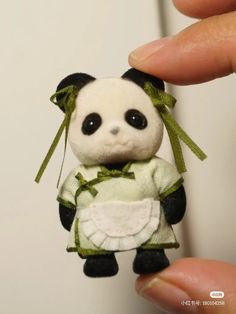 a small stuffed panda bear in a dress is being held by someone's hand