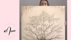 a woman holding up a painting with a tree on it