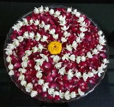 a bowl filled with red and white flowers on top of a black countertop next to a yellow button