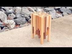 a wooden table sitting on top of a cement ground next to some rocks and trees