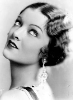 an old black and white photo of a woman with earrings on her head, looking off to the side