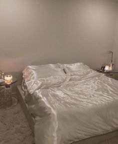 a white bed sitting in a bedroom next to two candles