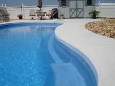 an empty swimming pool next to a white fence