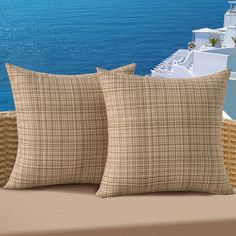 two pillows sitting on top of a couch next to the ocean