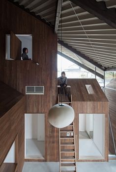 a man sitting on top of a wooden structure next to a staircase and window above it