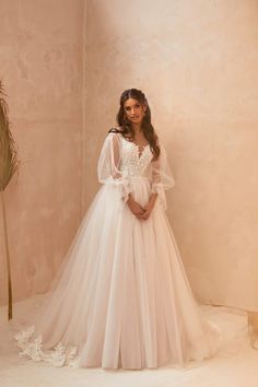 a woman in a white wedding dress standing next to a plant