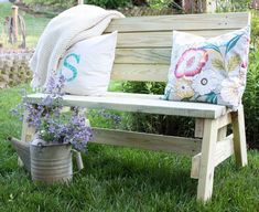 a wooden bench sitting on top of a lush green field next to a flower pot