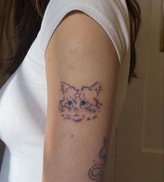 a woman's arm with a cat tattoo on the left side of her arm