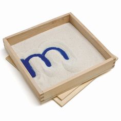 two wooden trays with sand in them and the letter m painted on one side