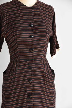 "Vintage 1950s cotton fitted dress. Vertical black and orange stripes. High collar, longer capped sleeves, seamed bust and nipped waist. Straight skirt with front pockets. Stream of front buttons for closure. State of garment | excellent Measurements ✂--- best fit | small bust | 35\" shoulders | not specified shoulder to waist | 15.5\" sleeves | not specified waist | 25-26\" hips | up to 39\" total length (shoulder to hem) | 39 \" ★★Visit The Shop★★ http://www.etsy.com/shop/seaofvintage ➸ Find t Short Sleeve Dresses With Vertical Stripes For Work, Classic Striped Cotton Dress, Classic Striped Dresses For Daywear, Fitted Short Sleeve Dress With Striped Collar, Fitted Short Sleeve Dress With Vertical Stripes, Fitted Dress With Vertical Stripes And Short Sleeves, Vintage Striped Fitted Dress, Retro Fitted Dress With Vertical Stripes, Fitted Retro Dresses With Vertical Stripes