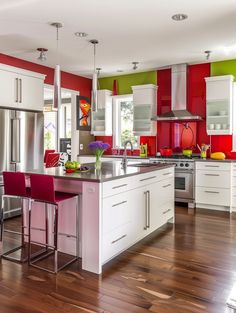 a kitchen with red and green walls, white cabinets and stainless steel appliances in it