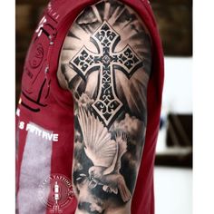 a man with a cross and dove tattoo on his arm is wearing a red shirt