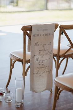 two chairs and a table with a sign hanging from it's back, next to some glasses